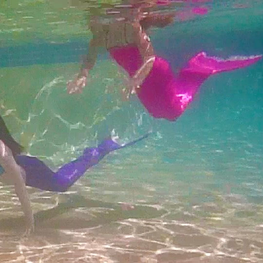 Two girls wearing pink and purple swimmable mermaid tails Brisbane Australia