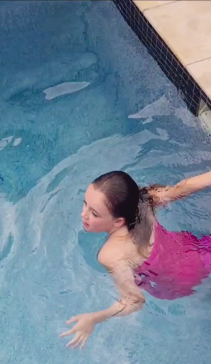 Girl wearing a pink swimmable mermaid tail swimming in a pool Brisbane Australia