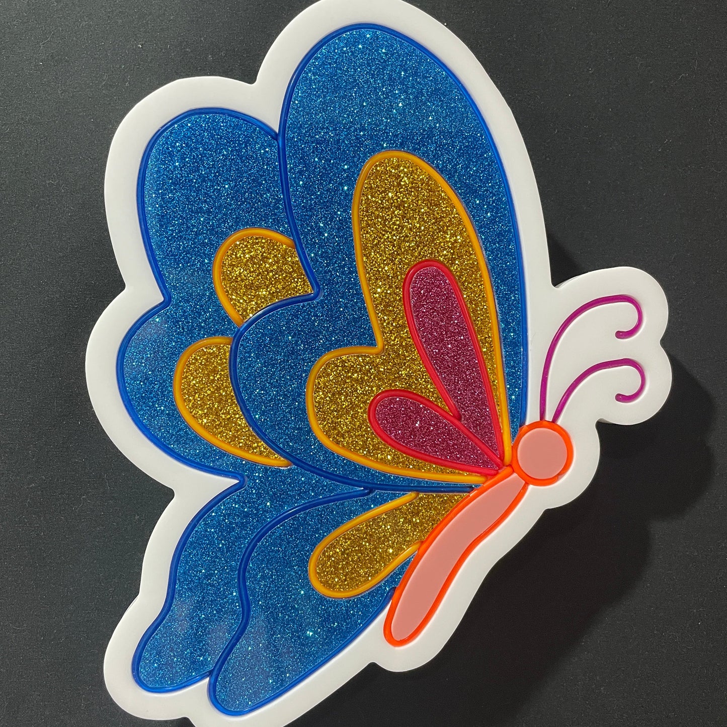Blue, gold and pink butterfly with its wings closed neon light not lit up