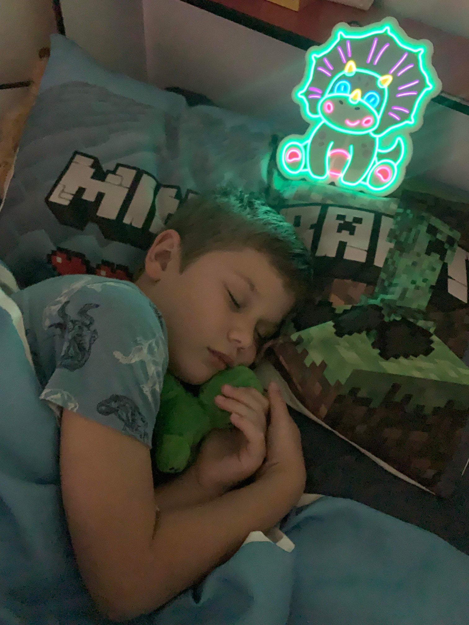 Boy asleep with his Triceratops neon nightlight resting on his pillow Brisbane Australia