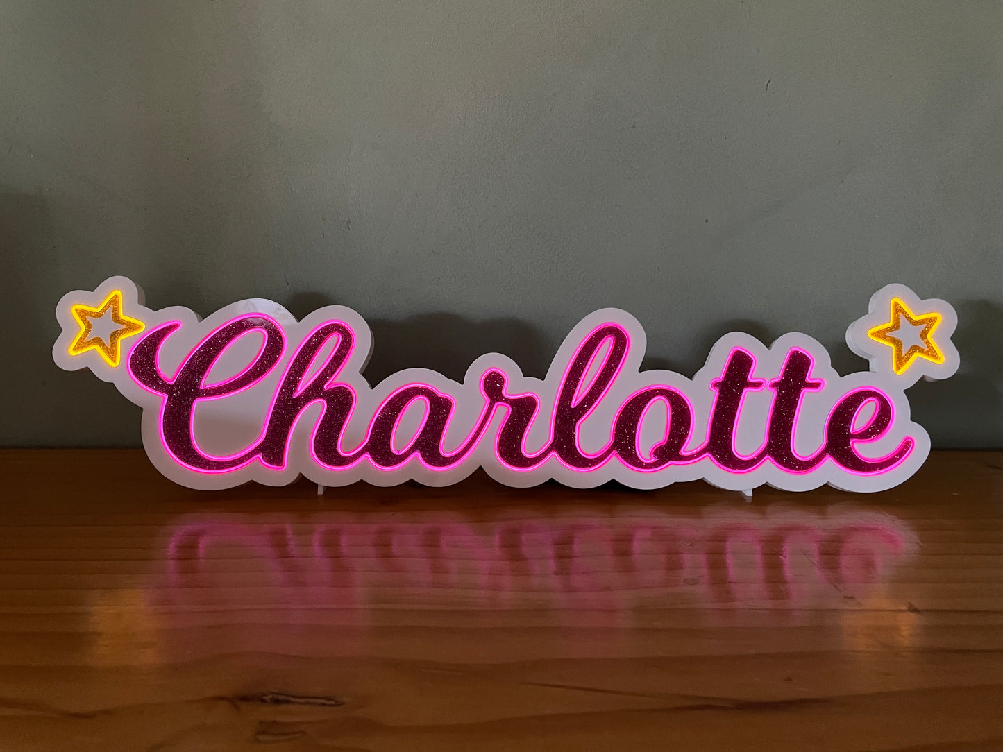 Charlotte neon name light in pink with a star at each end displayed lit up