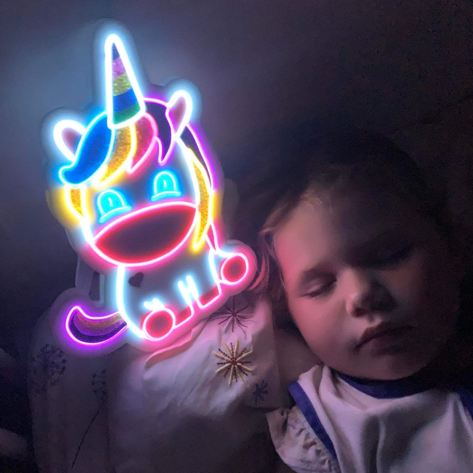 Child asleep with her baby unicorn neon light resting on her pillow Brisbane Australia