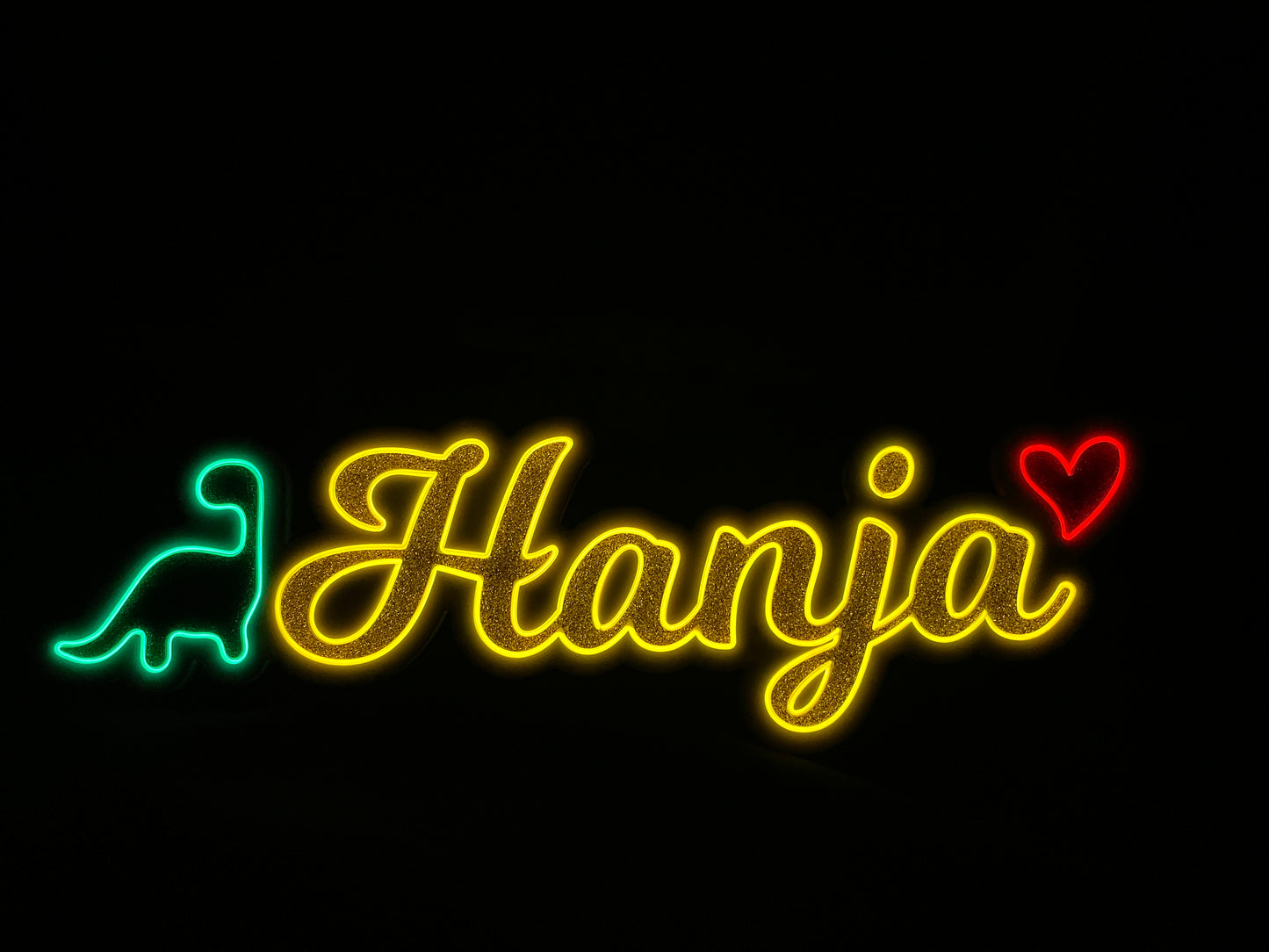 Neon name light in gold writing with a green dinosaur and a red heart lit up