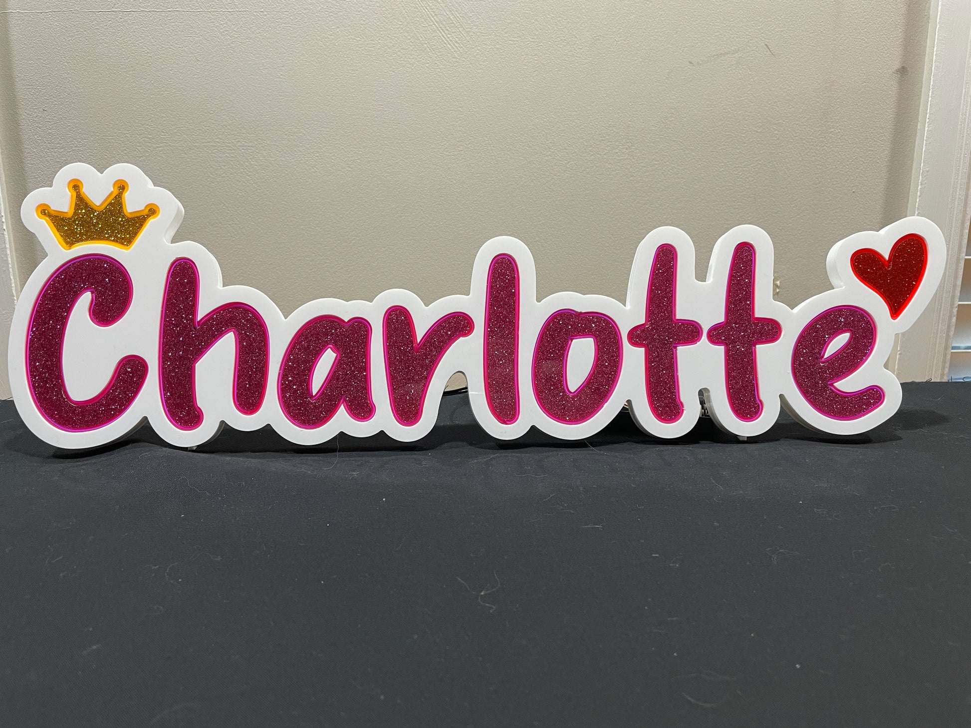Charlotte neon name light in pink with a gold crown at the beginning and a heart at the end displayed  not lit up