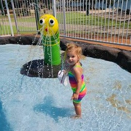 Toddler playing in a pool wearing bright rainbow singlet cop and shorts (2) Brisbane Australia