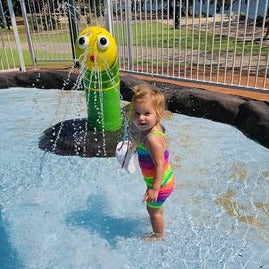Toddler playing in a pool wearing bright rainbow singlet cop and shorts Brisbane Australia