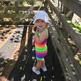 Toddler wearing bright rainbow singlet cop and shorts Brisbane Australia