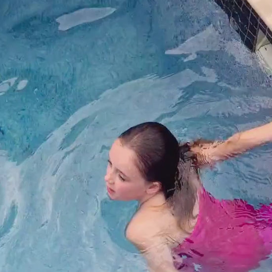 Girl wearing a pink swimmable mermaid tail swimming in a pool Brisbane Australia