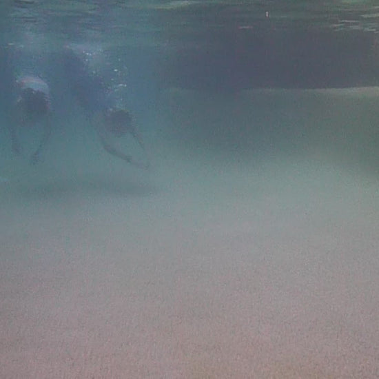 Two girls swimming wearing swimmable mermaid tails with a monofin in the bottom Brisbane Australia
